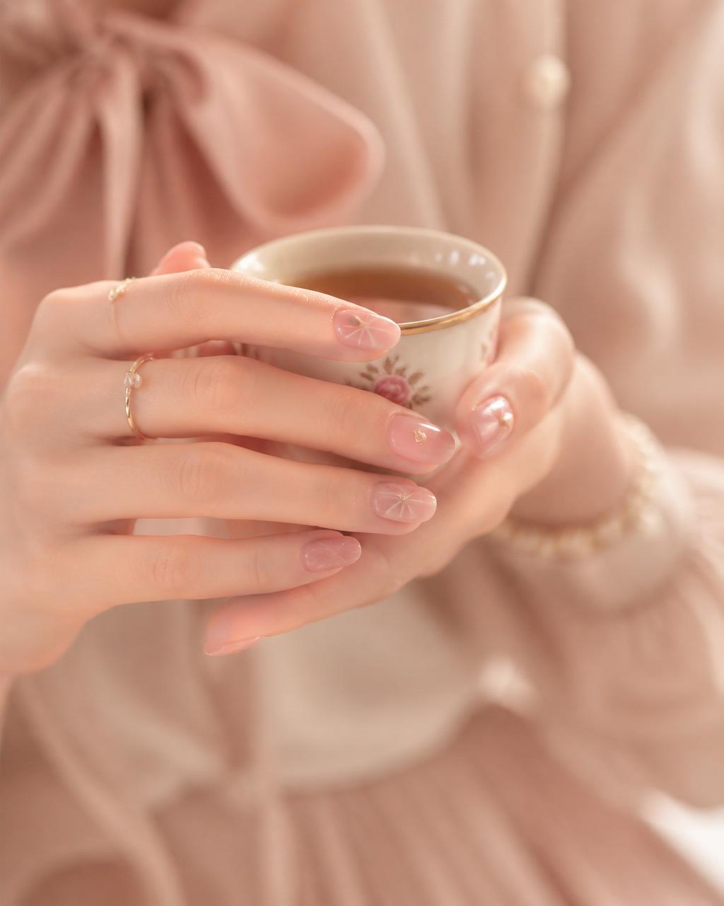 Mãos delicadas com nail art segurando xícara de chá